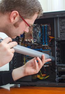 Man using vacuum to clean out computer